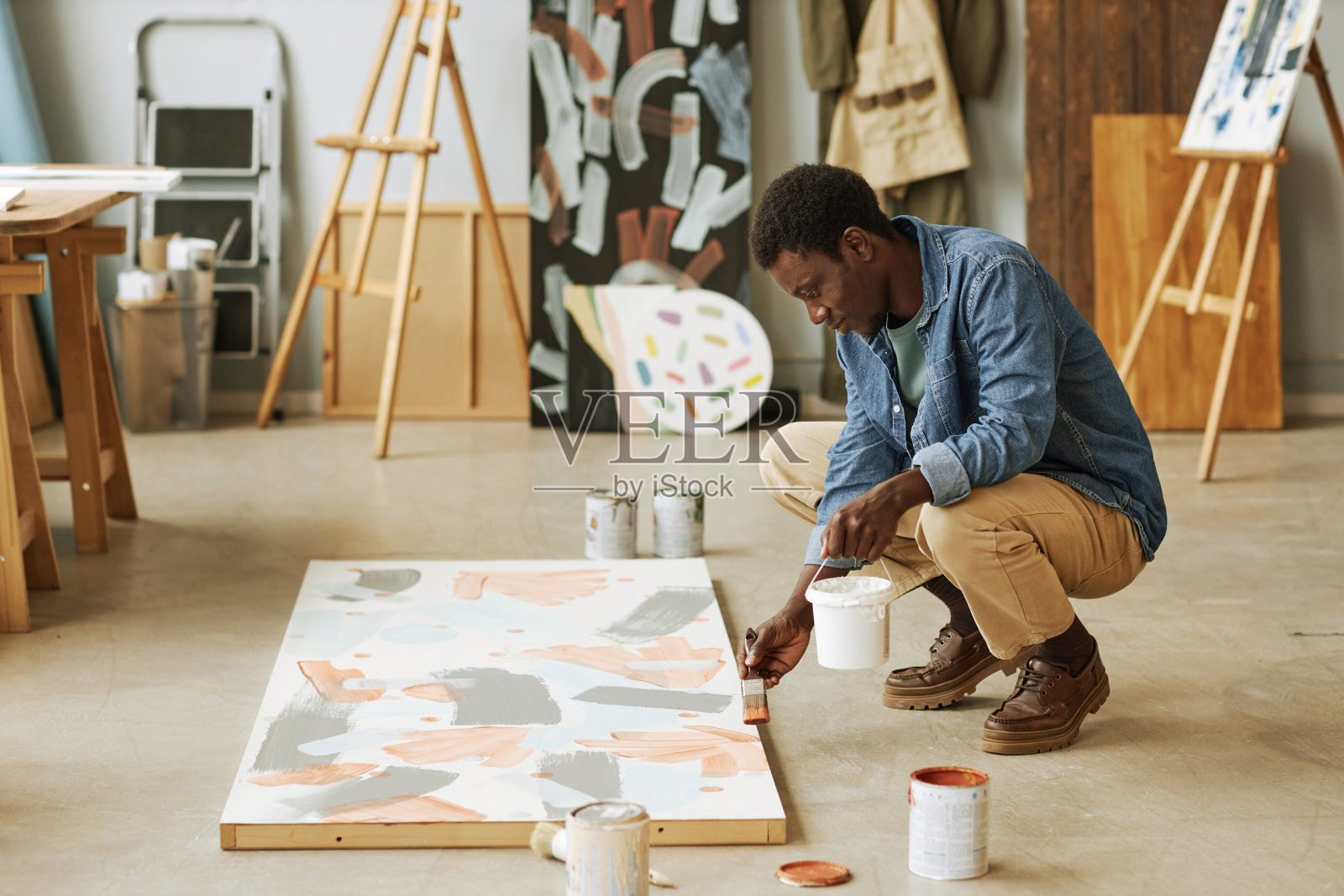 年轻人坐在深蹲和弯腰帆布未完成的艺术品照片摄影图片