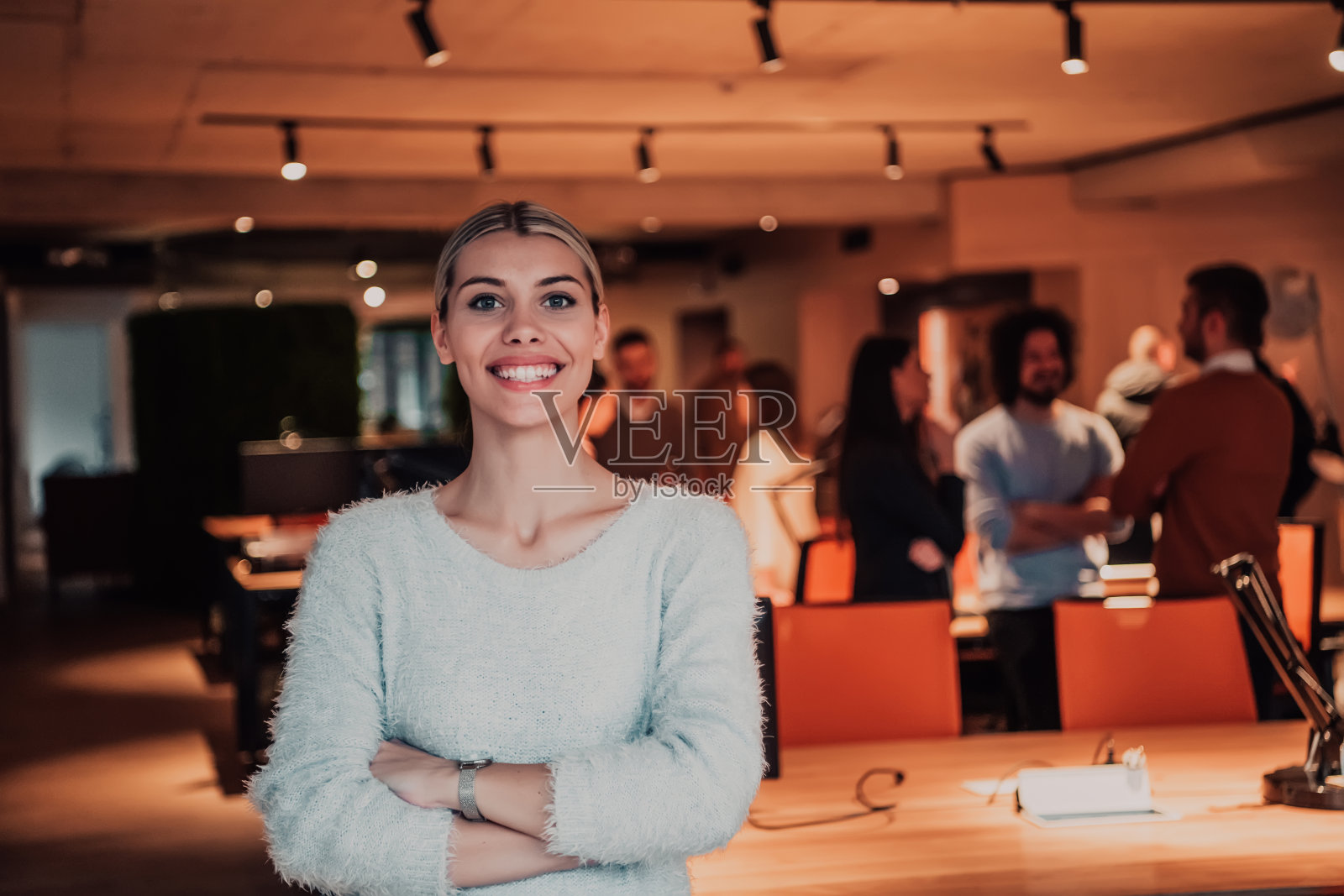 肖像照片的一个现代金发女郎在一个现代的办公室工作休息。后台是负责项目的团队照片摄影图片