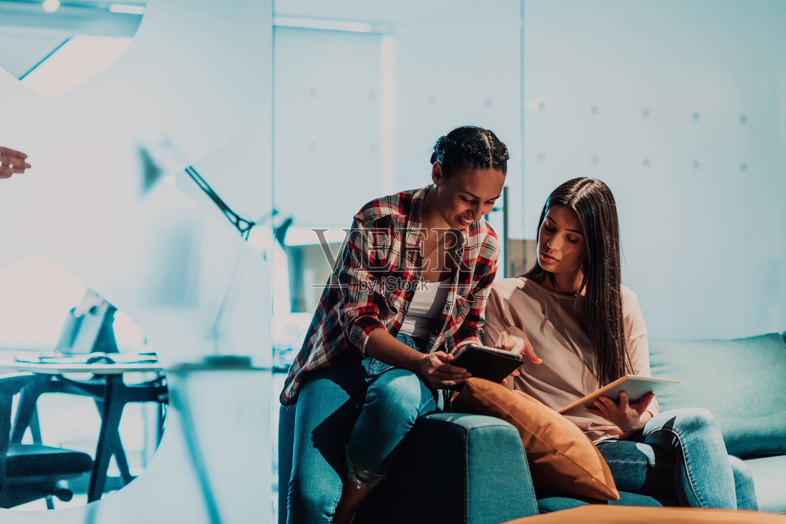 两个年轻的女人在一个现代化的办公室里一起用笔记本电脑解决问题照片摄影图片