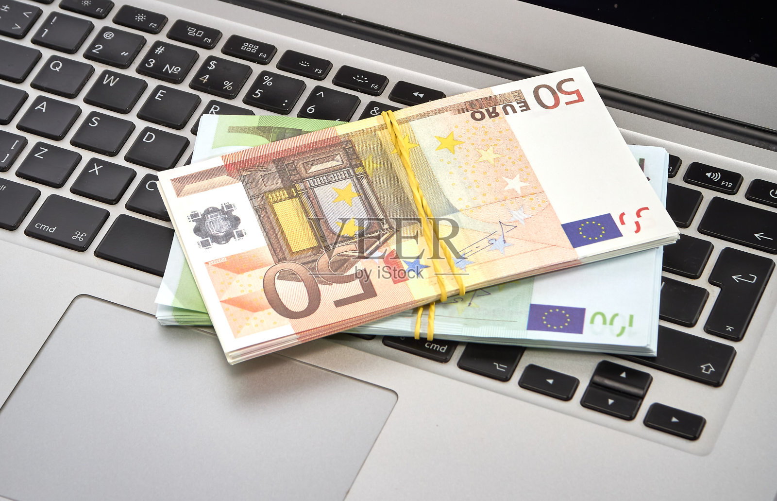 一包包100欧元和50欧元的钞票躺在电脑键盘上照片摄影图片