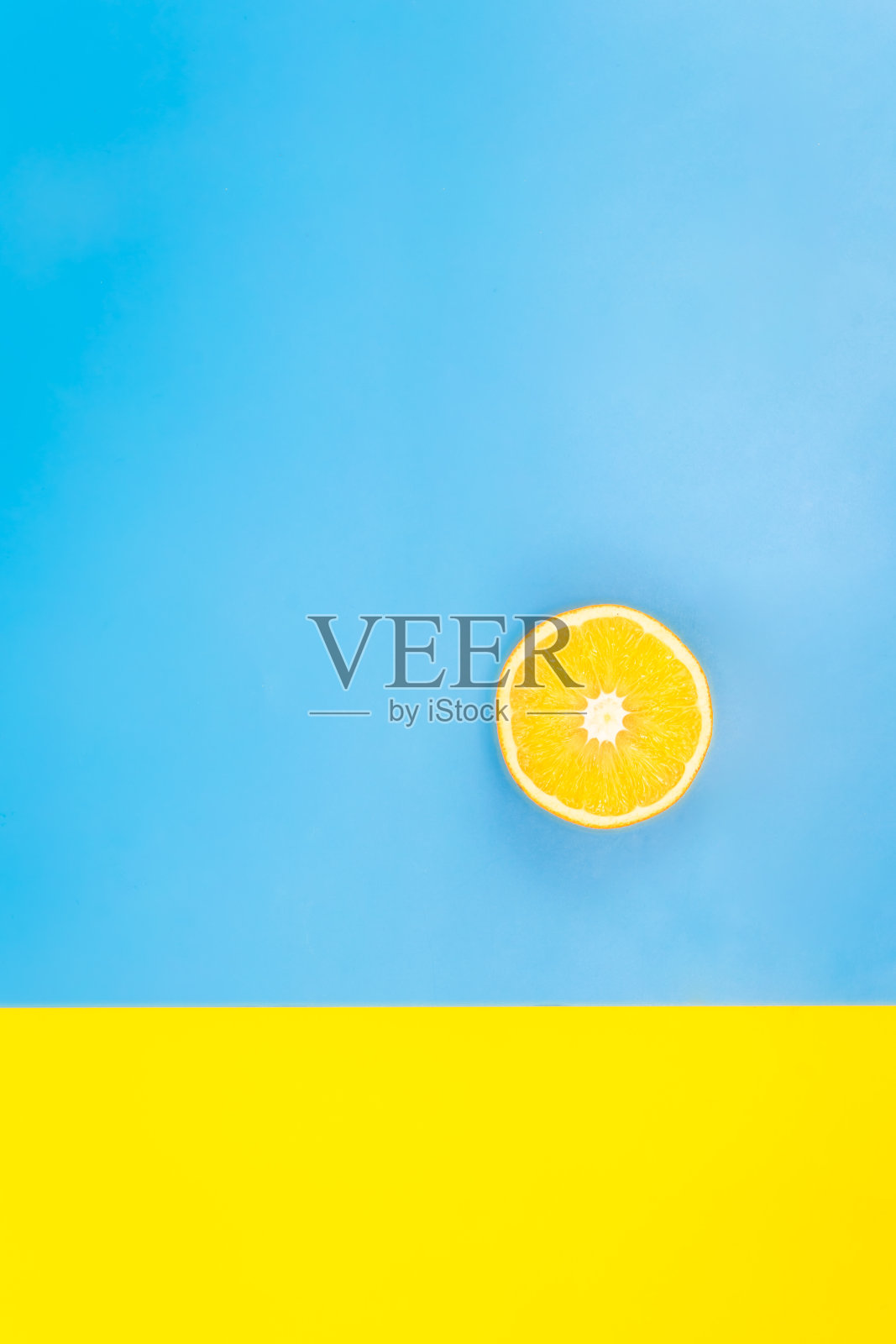 蓝色和黄色背景上的半个橙子,平面,极简主义。照片摄影图片