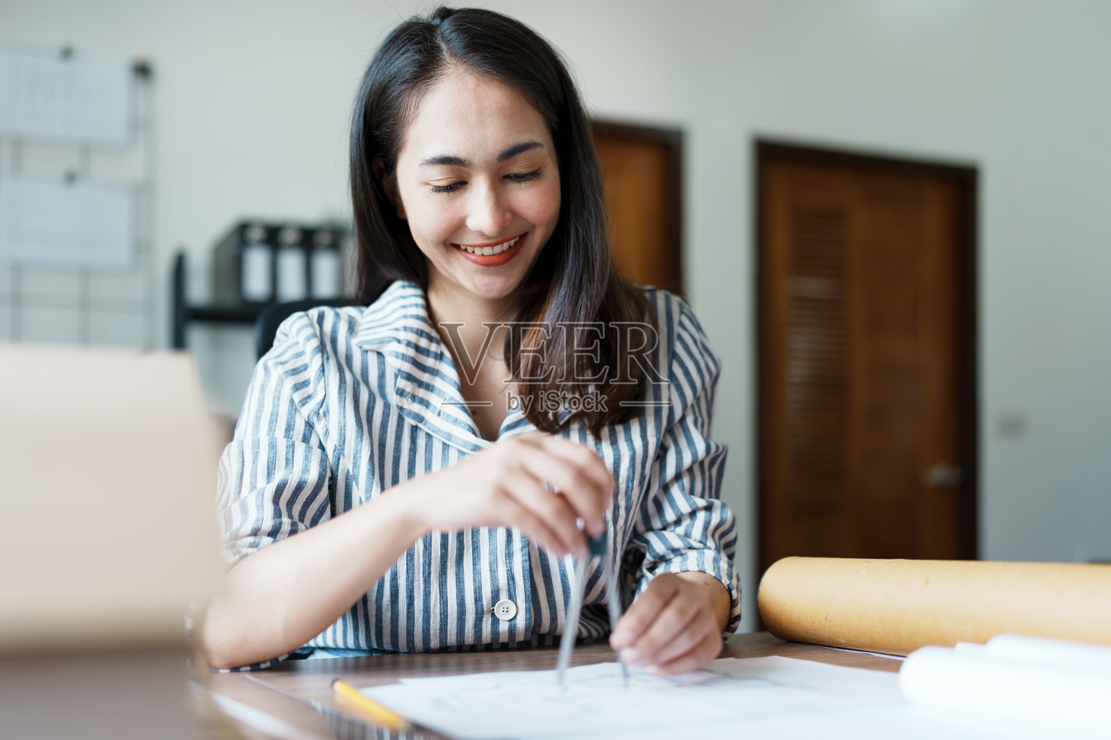 一名亚洲女工程师的肖像正在设计房屋结构和建筑,使用蓝图、尺子、铅笔、隔板和建筑模型来工作照片摄影图片