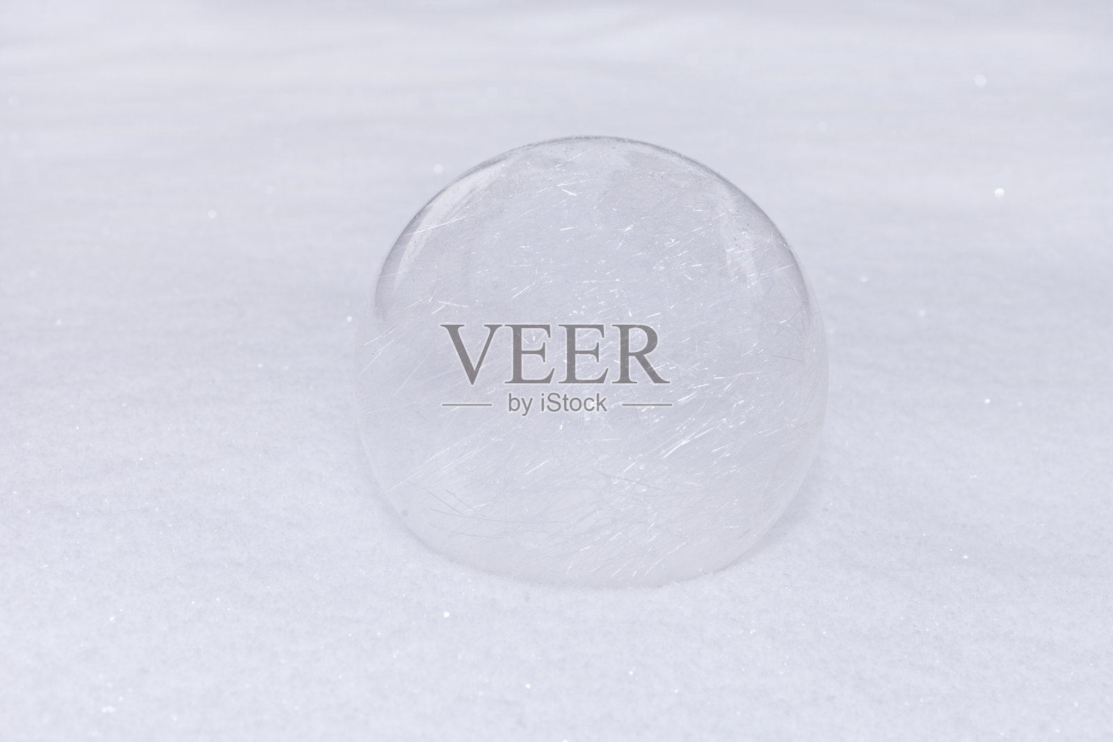 白色雪地上的玻璃球或透明的小玩意。冬季在户外。灿烂的球体雪景。照片摄影图片