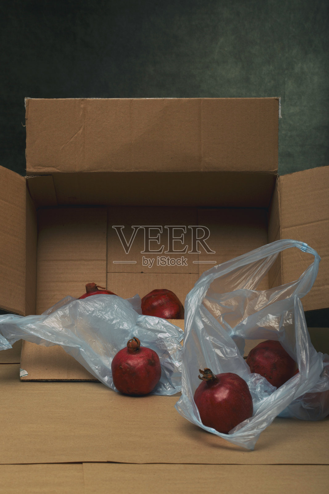 成熟的红石榴放在桌上的纸板箱里照片摄影图片