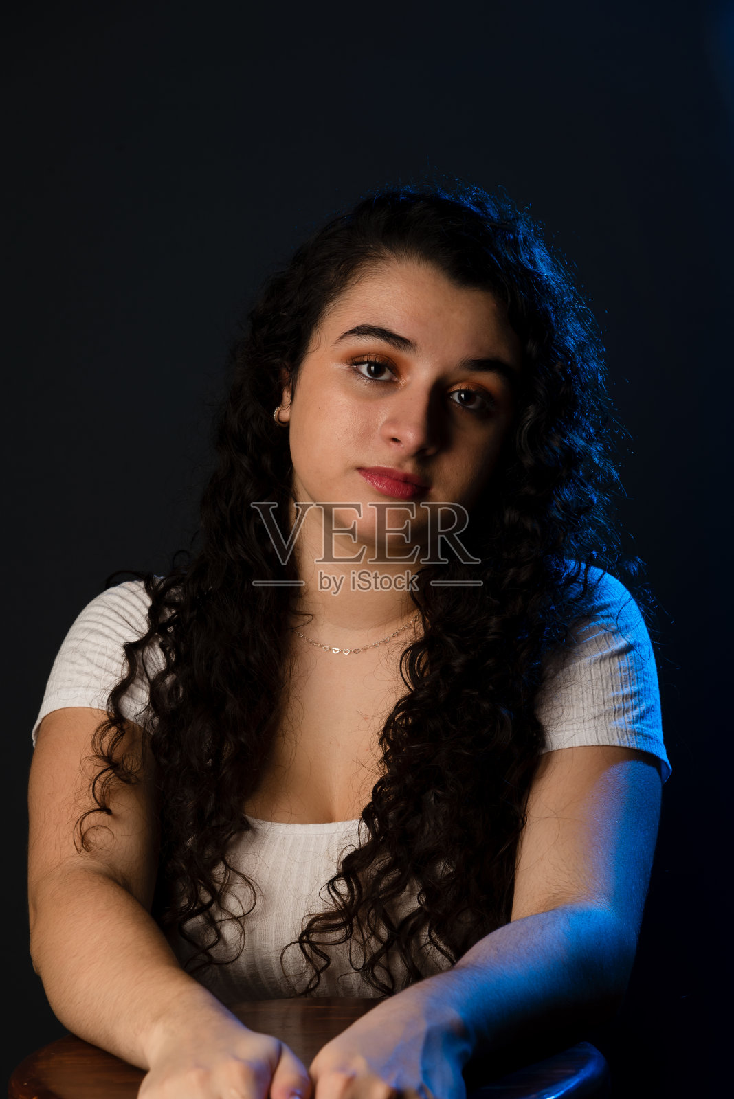 年轻女子坐在木凳上看着相机的肖像。照片摄影图片