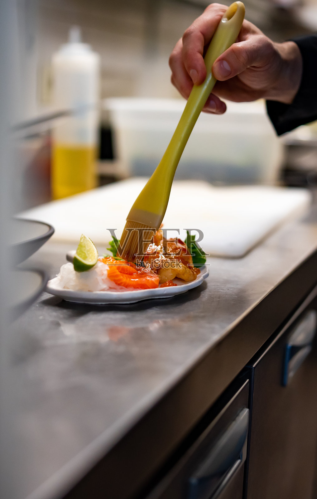 厨师在厨房烹饪三文鱼、鱼片和虾片配沙拉照片摄影图片