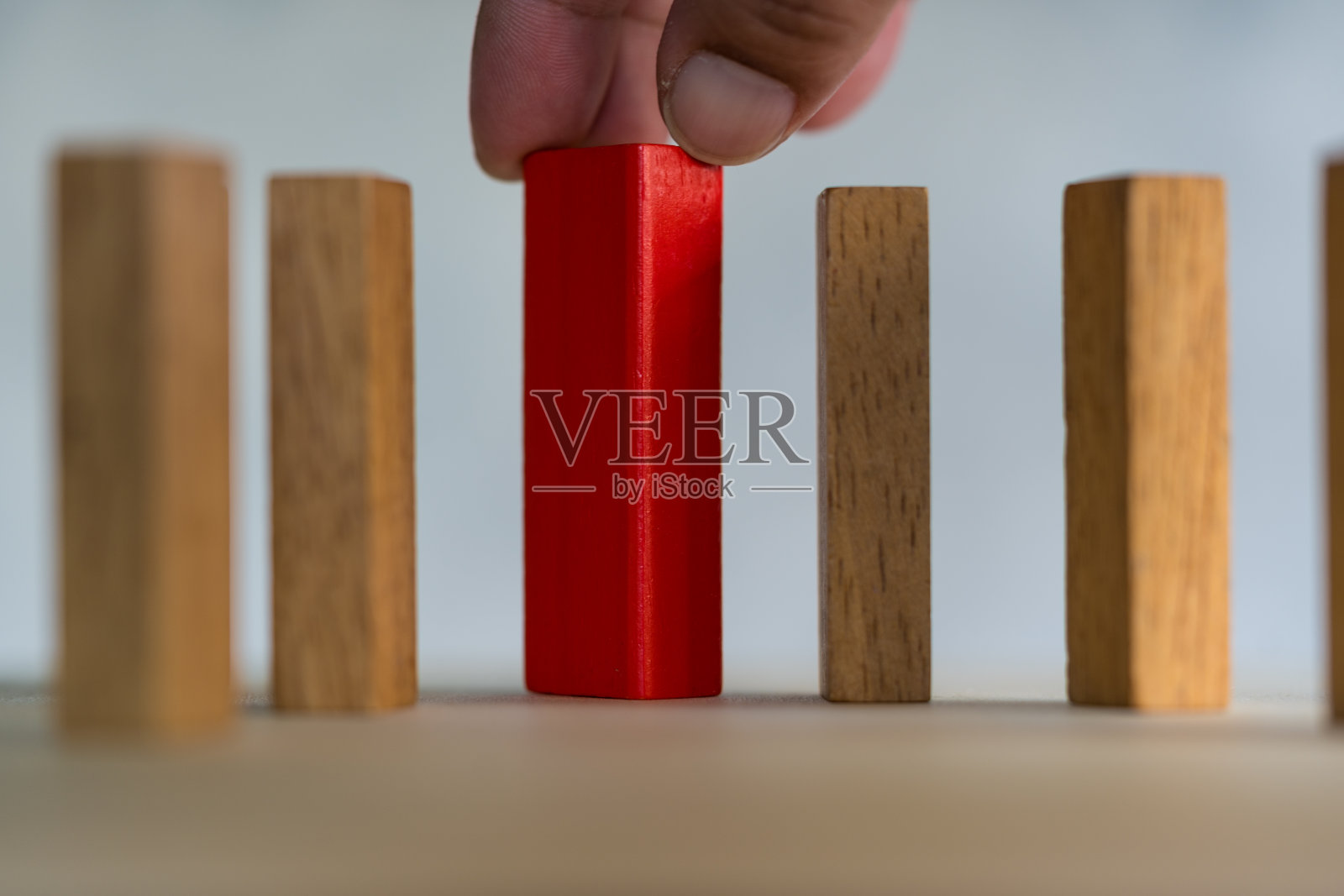 从众多候选人中选择创意人的商业理念又各不相同。近距离用手从许多木块中挑出一块红色木块。照片摄影图片