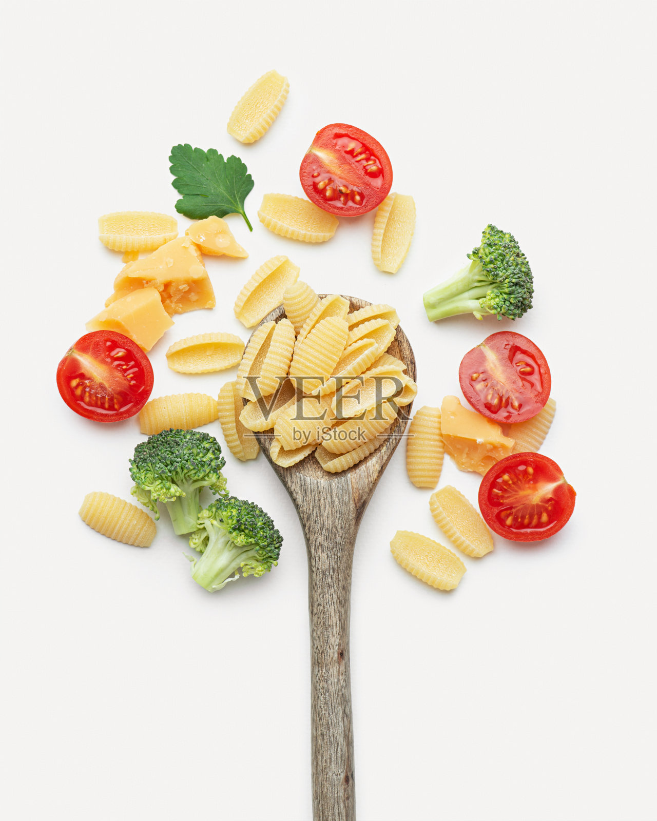 生意大利面配番茄、花椰菜、欧芹和帕尔马干酪,用木勺盛在白底上照片摄影图片