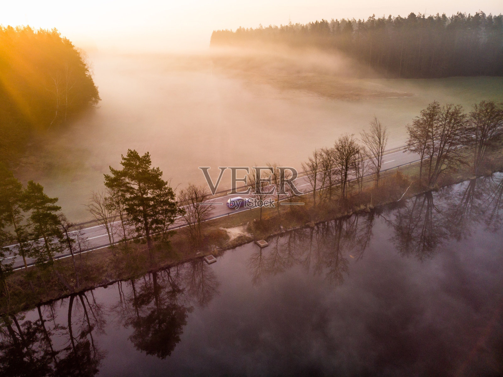 鸟瞰一辆行驶在湖边道路上的汽车,被朦胧的晨光照亮照片摄影图片