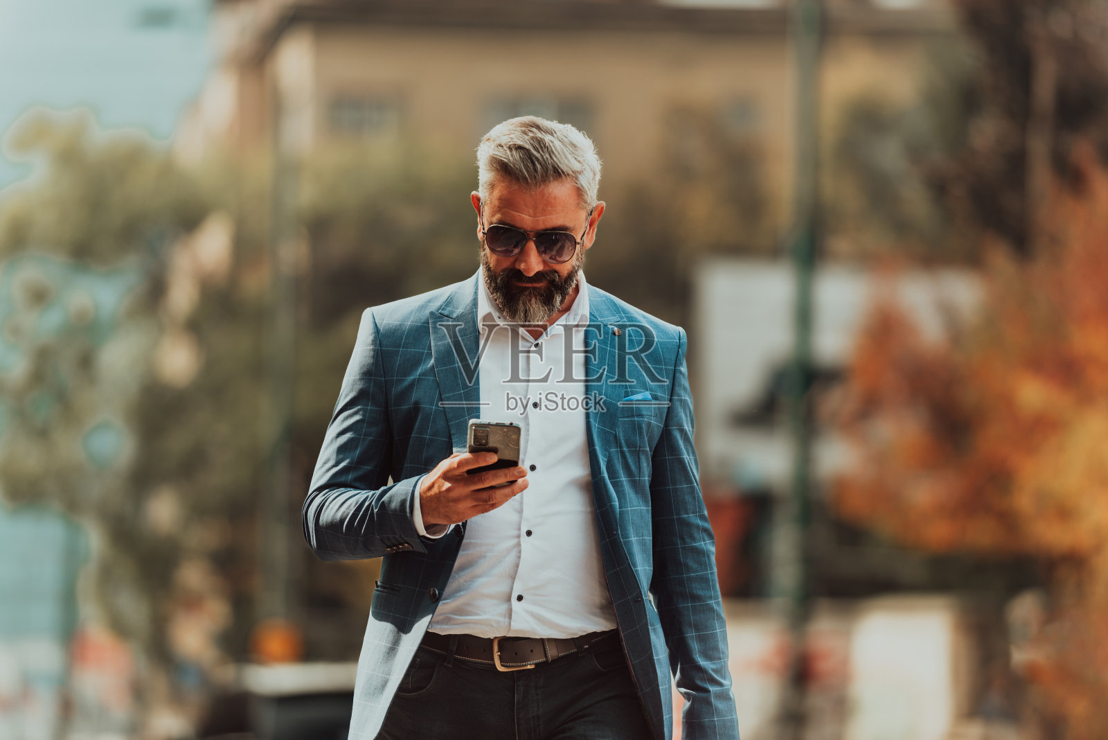 一位西装革履、戴着墨镜的商人背着包在城市里走来走去照片摄影图片