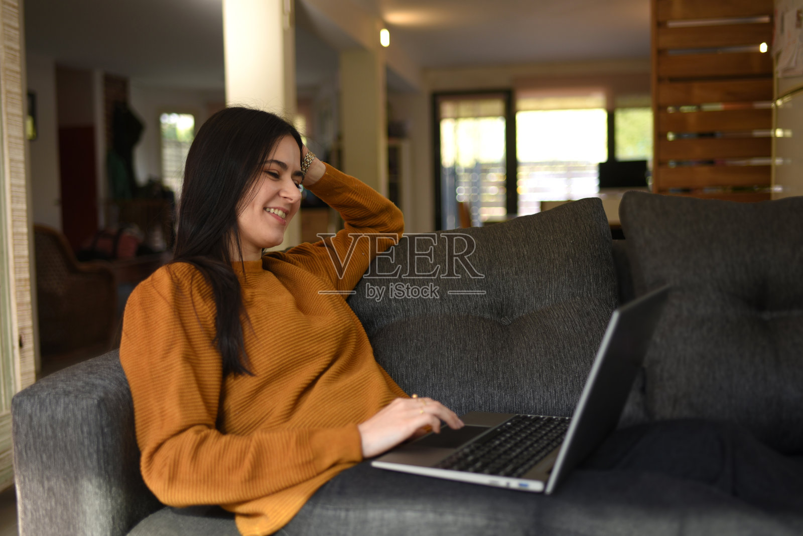女人坐在沙发上看笔记本电脑照片摄影图片