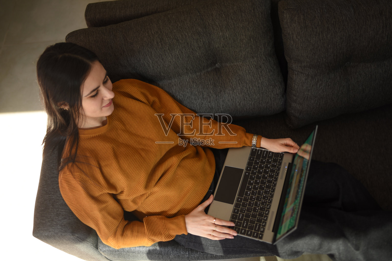 女人坐在沙发上看笔记本电脑照片摄影图片