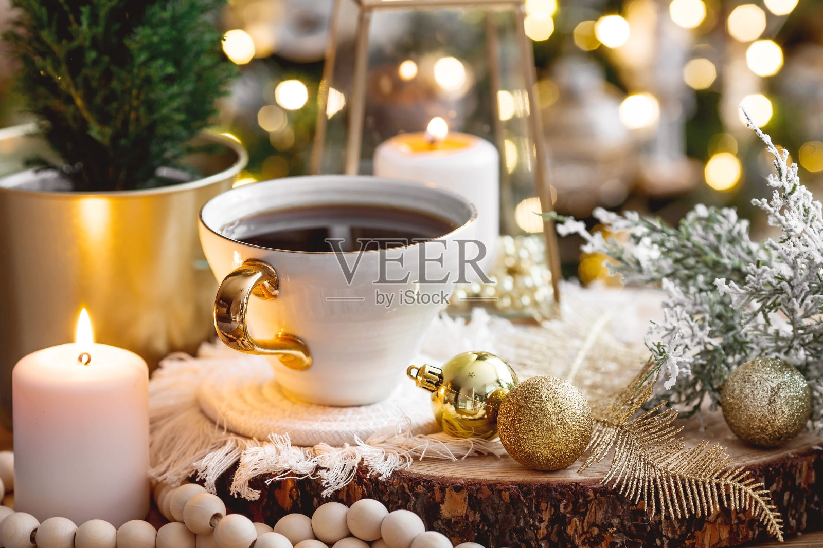 的生活方式。在圣诞假期里,一杯茶、一棵圣诞树、蜡烛和金球放在一张木桌上,背景是美丽的散景。静物。家的概念温馨、舒适照片摄影图片