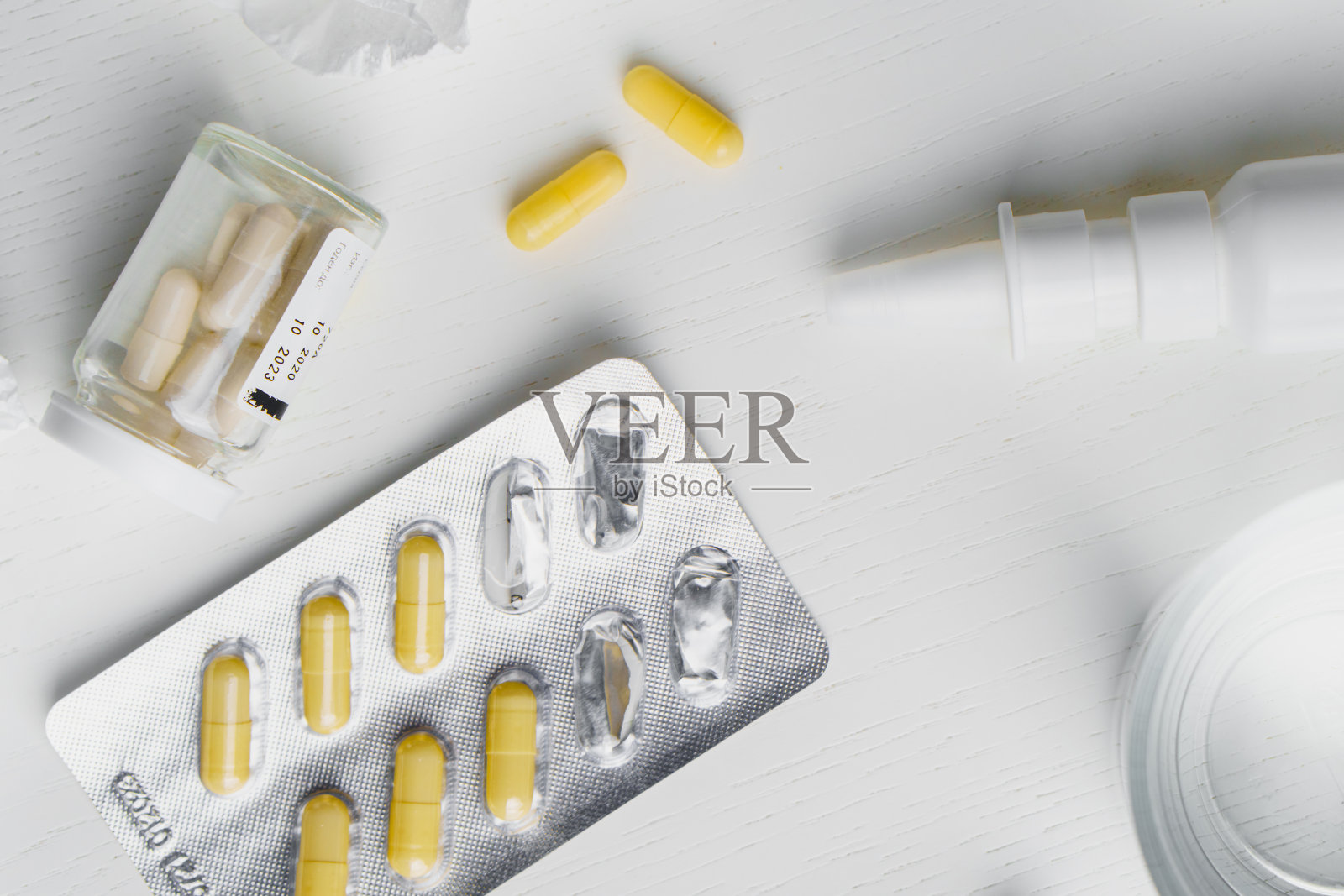 一杯水,喷鼻喷雾,水泡里的药片,桌子上放着用过的餐巾。流感治疗概念照片摄影图片