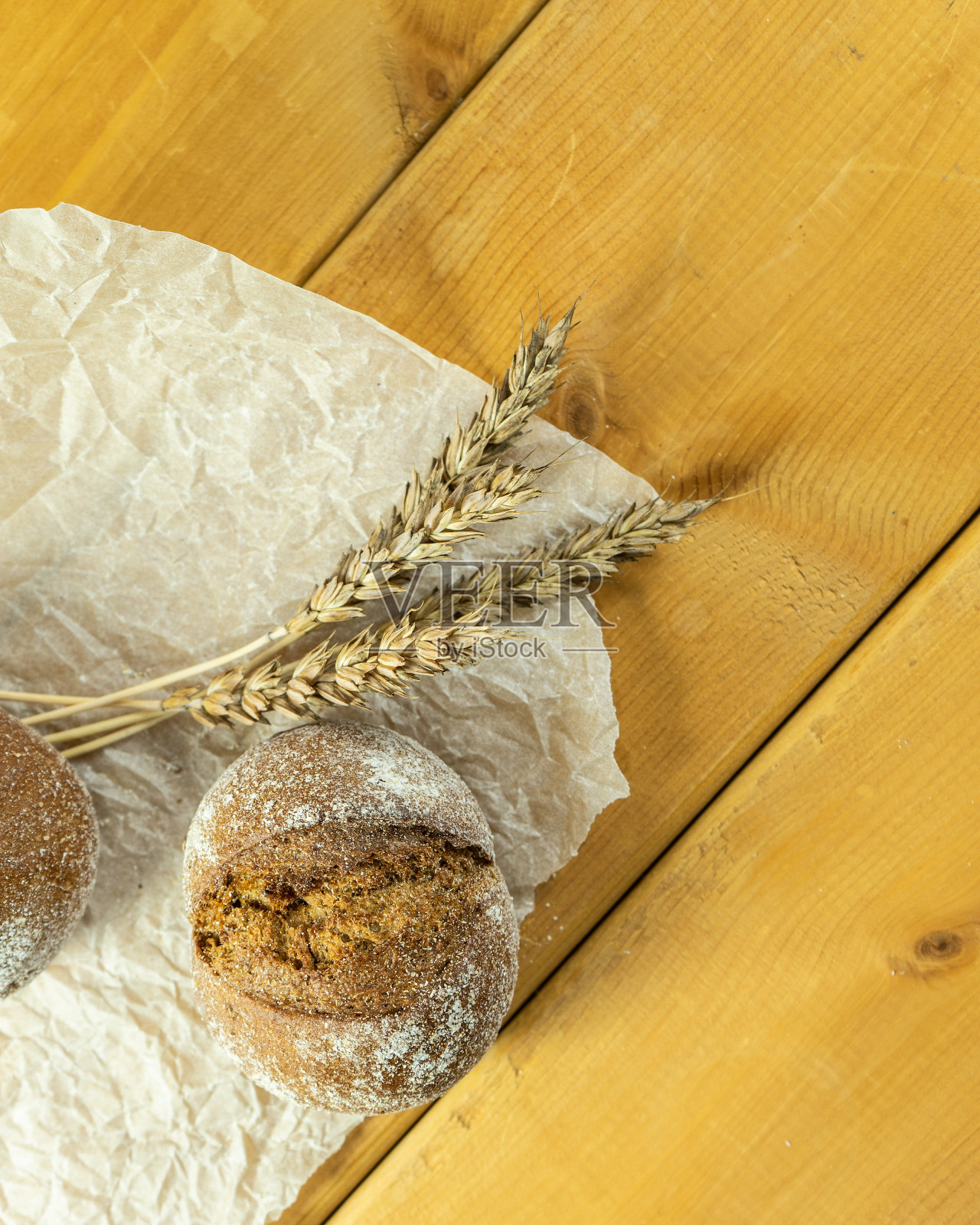 自制全麦酸面包,麦粒和小穗。小麦面包的小穗。新鲜小麦面包的小穗放在棕色的木质背景上。照片摄影图片