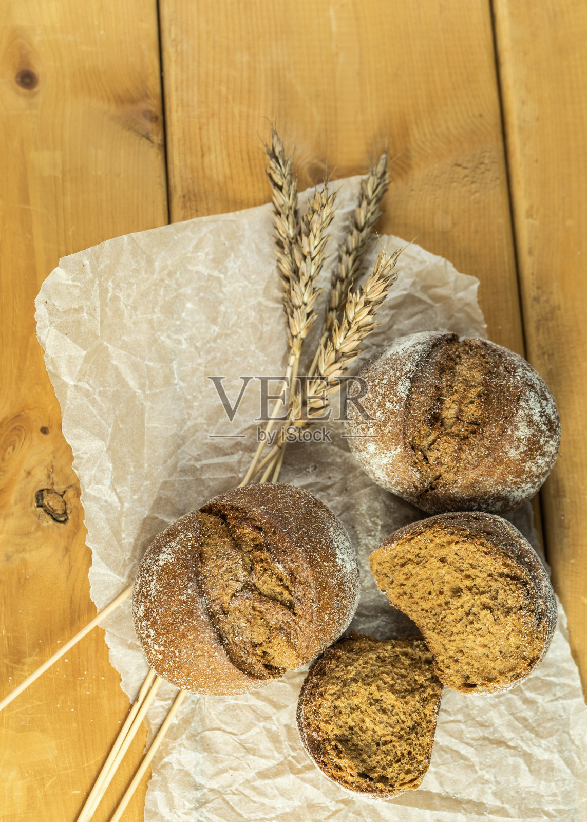 自制全麦酸面包,麦粒和小穗。小麦面包的小穗。新鲜小麦面包的小穗放在棕色的木质背景上。照片摄影图片