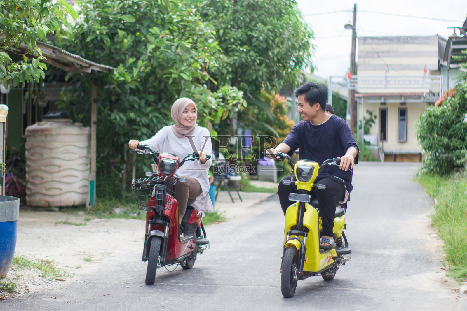 年轻夫妇在住宅区骑电动自行车照片摄影图片