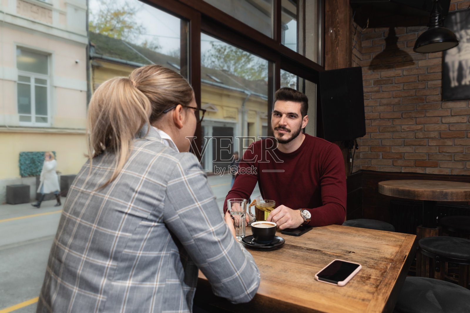 两个年轻的商业伙伴,男人和女人坐在自助餐厅里,一边喝着咖啡,一边研究新项目,交换想法和计划,让他们的公司有更好的表现。照片摄影图片