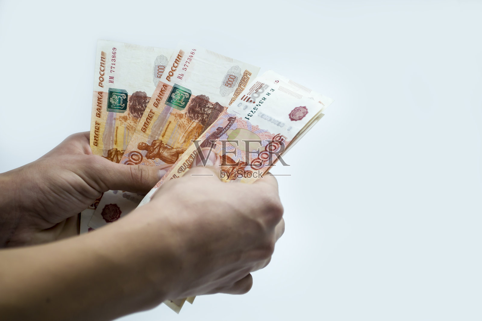 一个人手里数着俄罗斯的5000张纸币。照片摄影图片