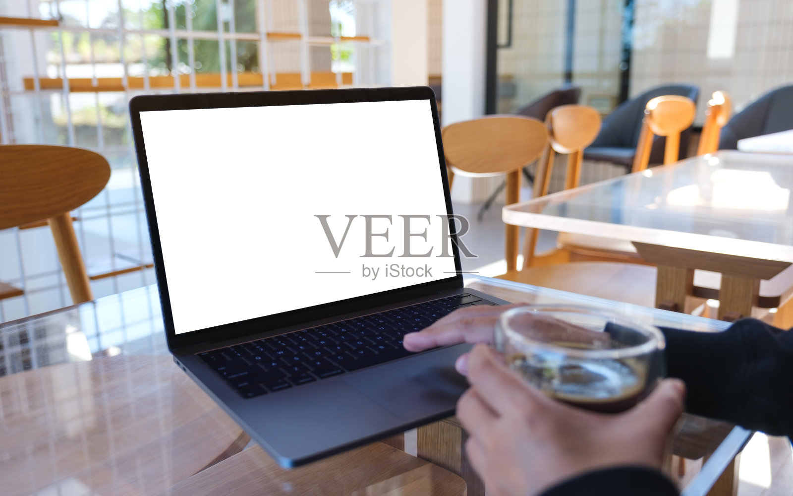 一个女人在喝咖啡的时候在笔记本电脑上用空白的白色桌面屏幕打字的模型照片摄影图片