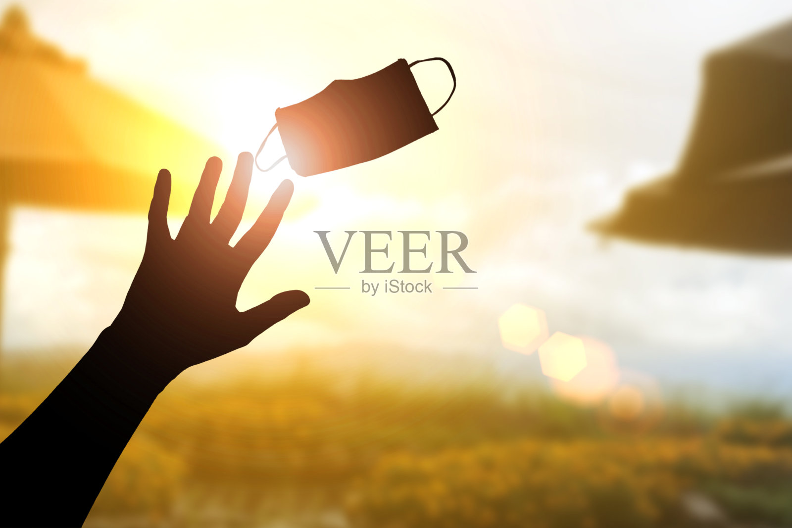 希望剪影,积极应对冠状病毒概念。手举医用口罩。手势表示再见。起飞面罩和深呼吸呼吸新鲜空气照片摄影图片