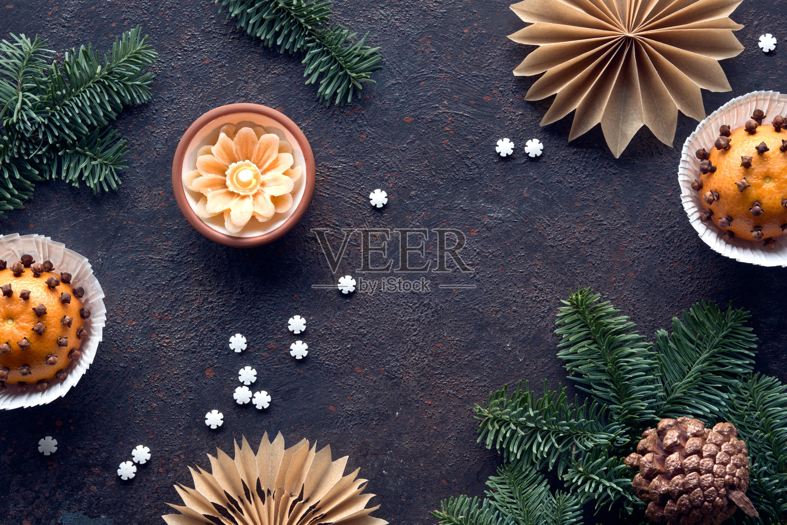 冬天的黑色背景与芳香的香精球。经典的装饰——丁香橘色。用棕色烘焙纸、松果、冷杉树枝和燃烧的蜡烛手工制作的纸星星。照片摄影图片