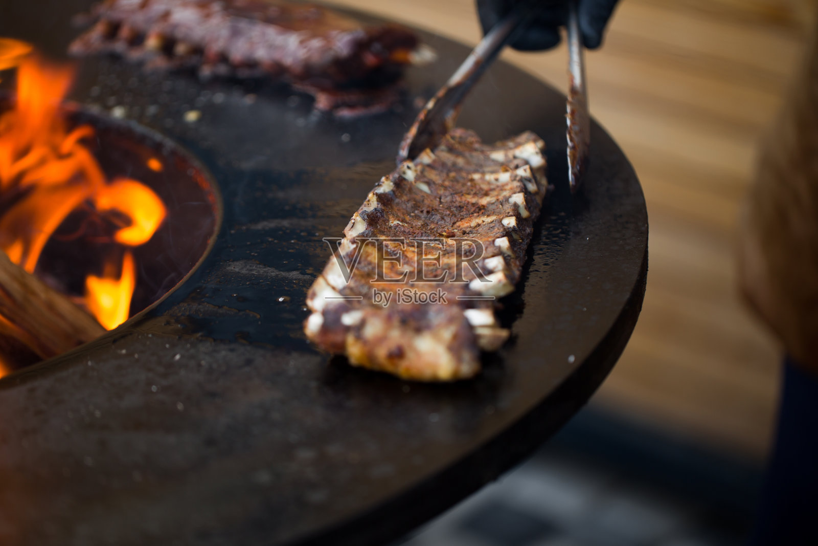 烤架上的烤猪小排骨配烧烤酱。节日街头小吃照片摄影图片