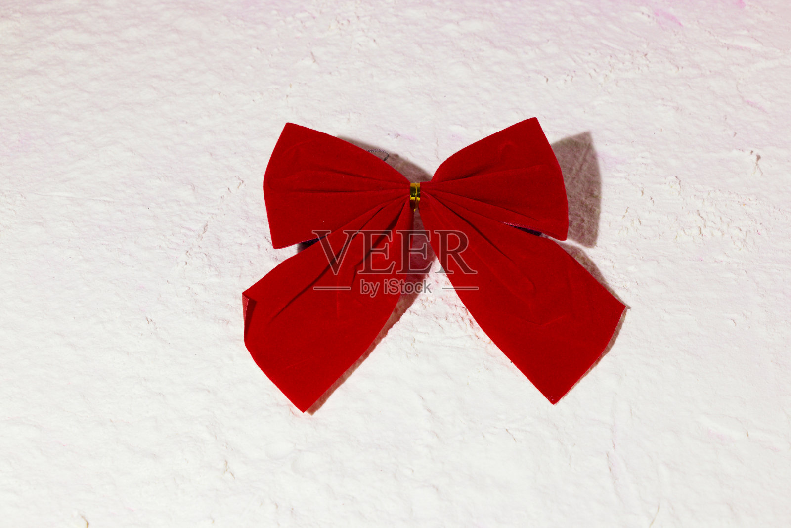 红蝴蝶结在雪中,创意假日概念照片摄影图片