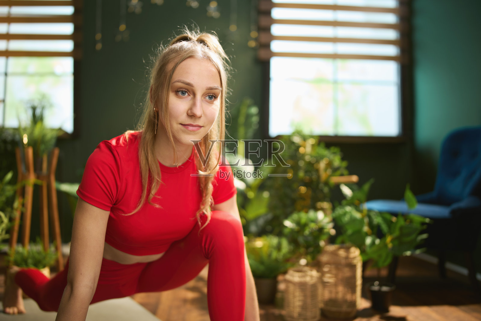 穿着红色健身服的女人在绿色的家里做瑜伽照片摄影图片