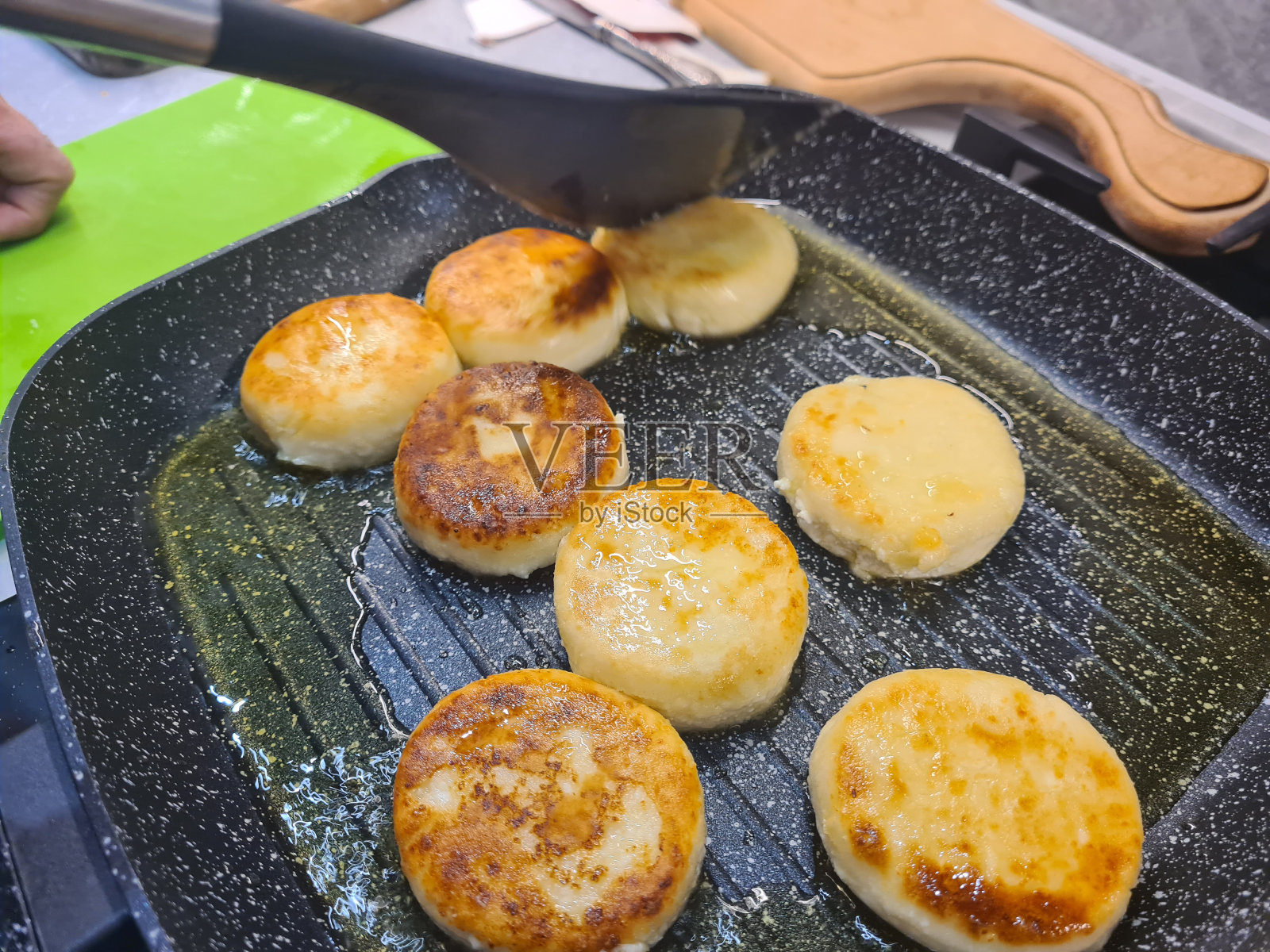 芝士蛋糕在厨房的平底锅里煎。照片摄影图片