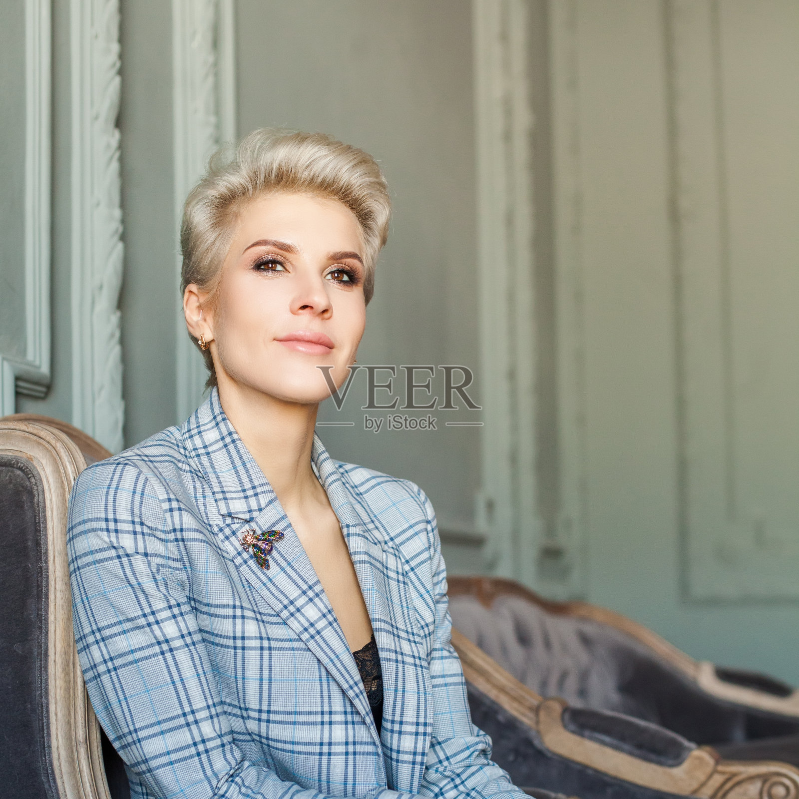 完美的金发短头发的女人在蓝色西装是看着相机照片摄影图片