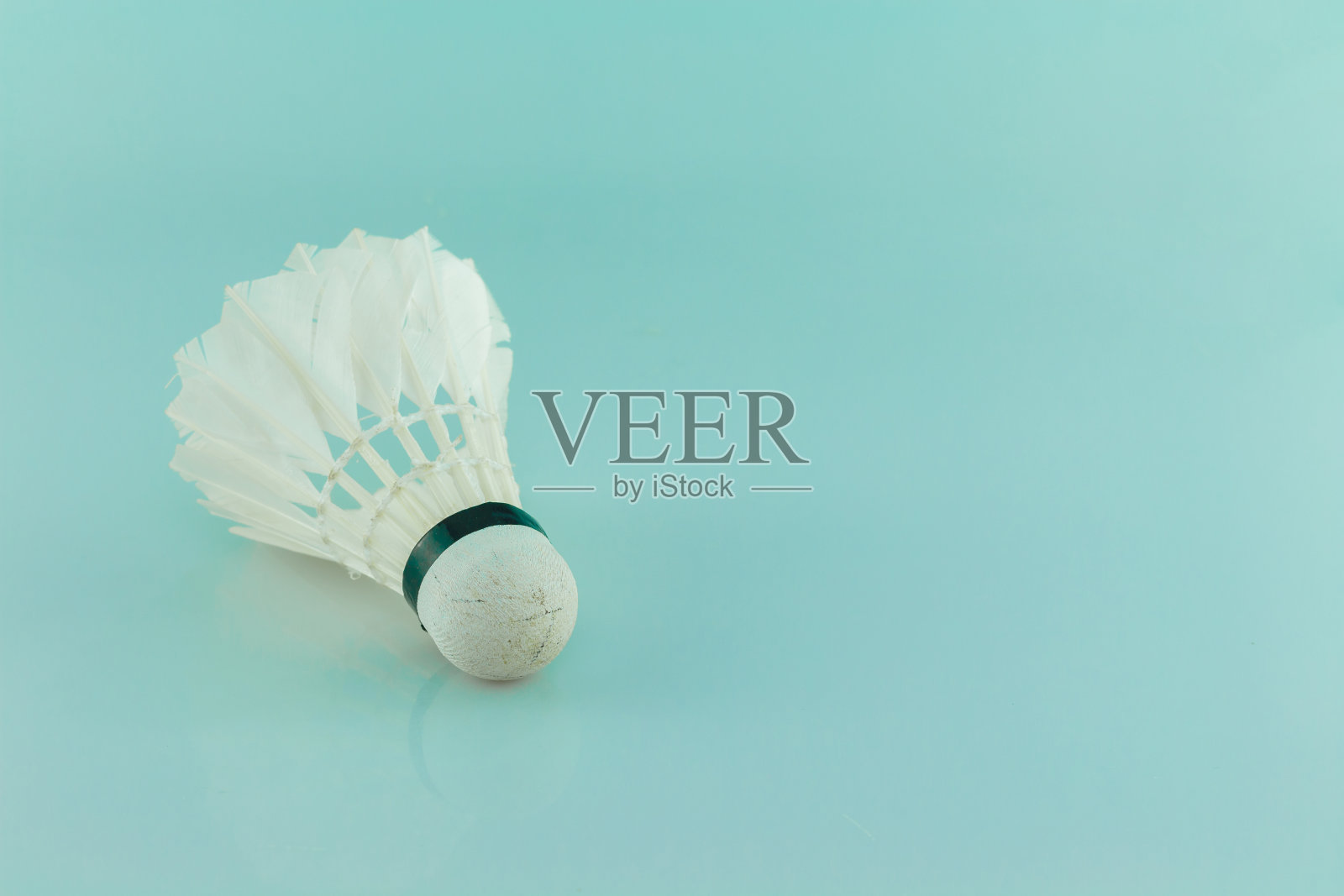 用过的毽子放在绿色的背景上。照片摄影图片