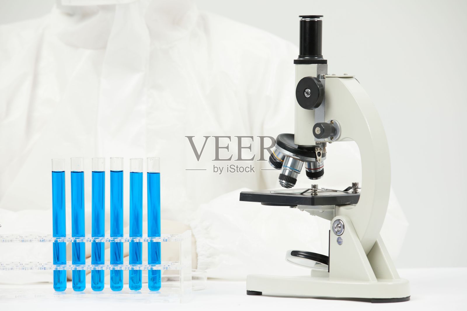 医生在医学实验室用光学显微镜工作,桌上放着试管照片摄影图片