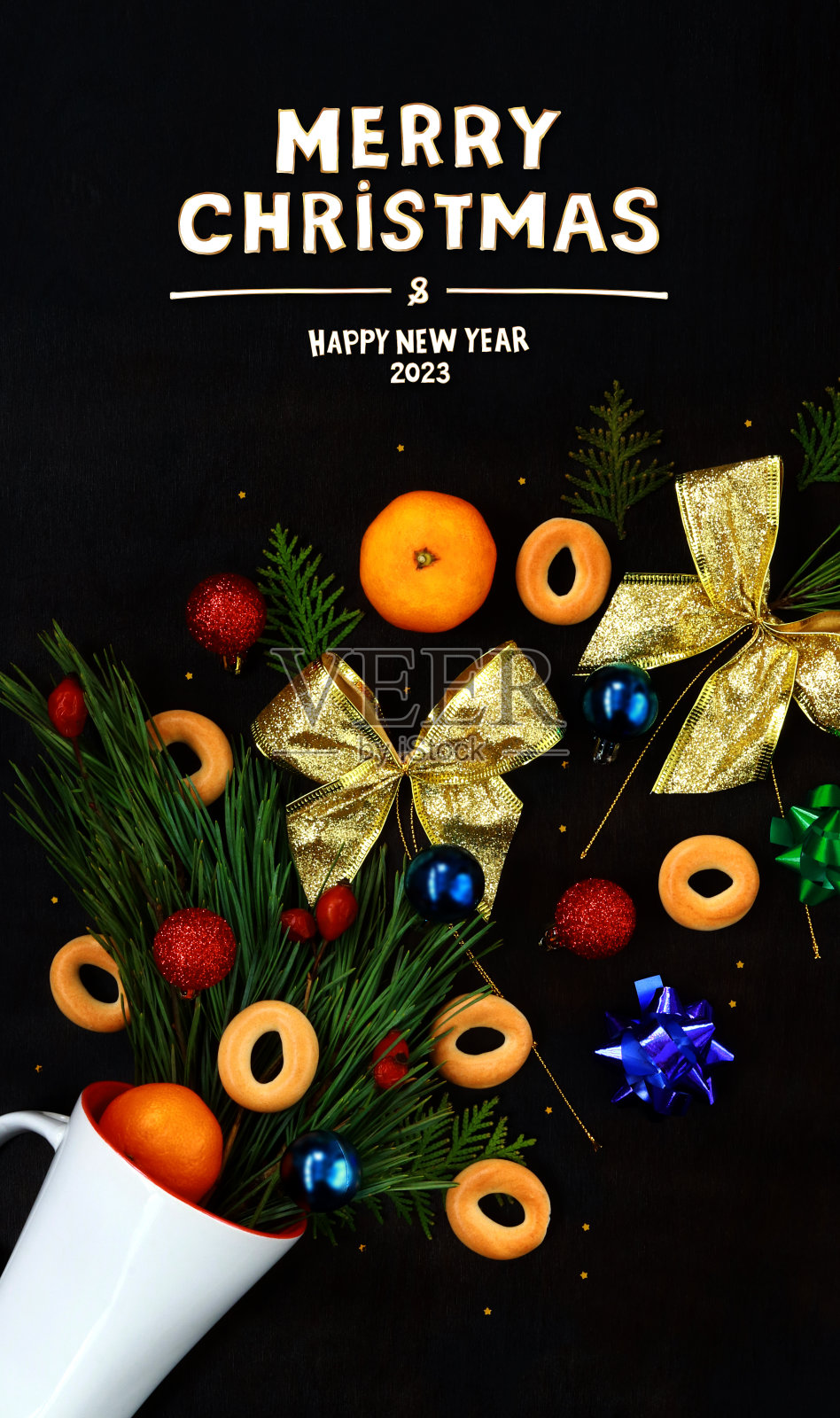 圣诞装饰从一个白色的杯子里倒出来,背景是黑色的木头。圣诞快乐,2023年新年快乐照片摄影图片