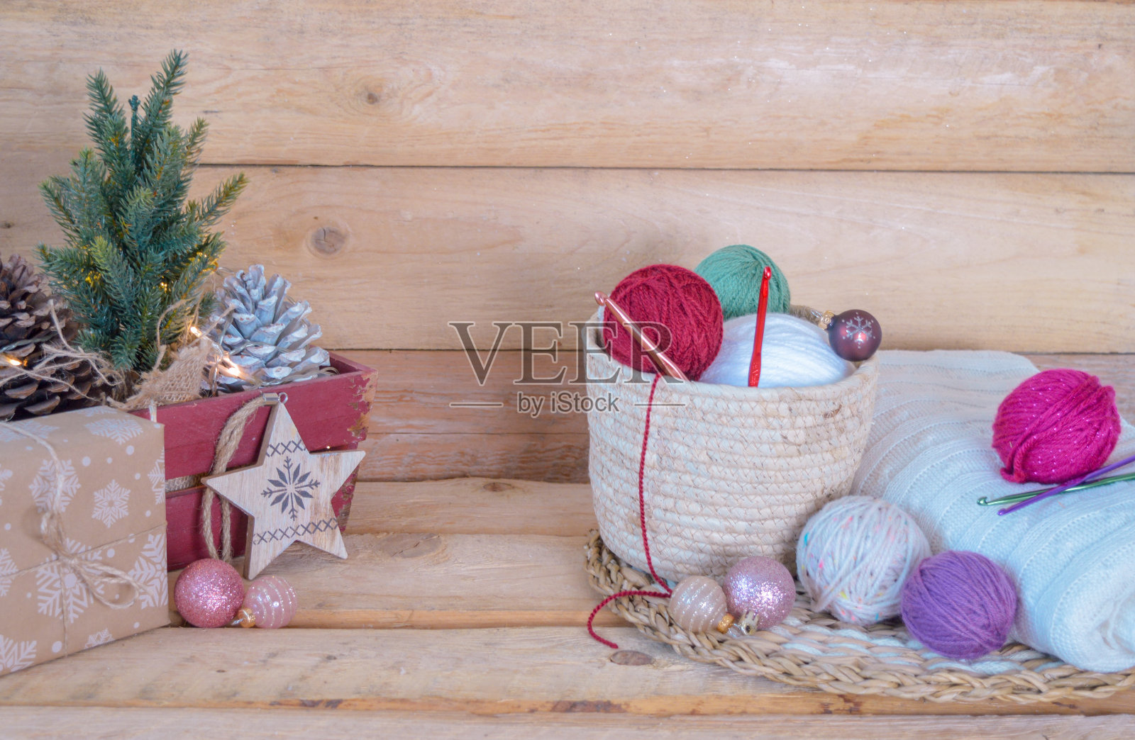 羊毛彩色球与钩针钩在一个木盒子,与圣诞球在木地板照片摄影图片
