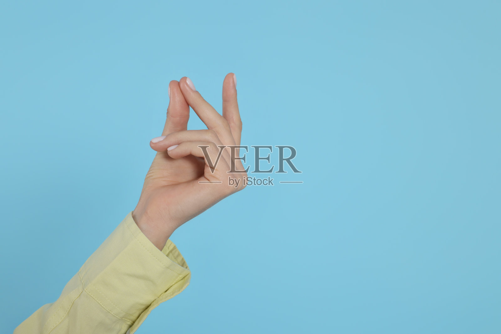 女人在浅蓝色背景上打响指,手部特写。文本空间照片摄影图片