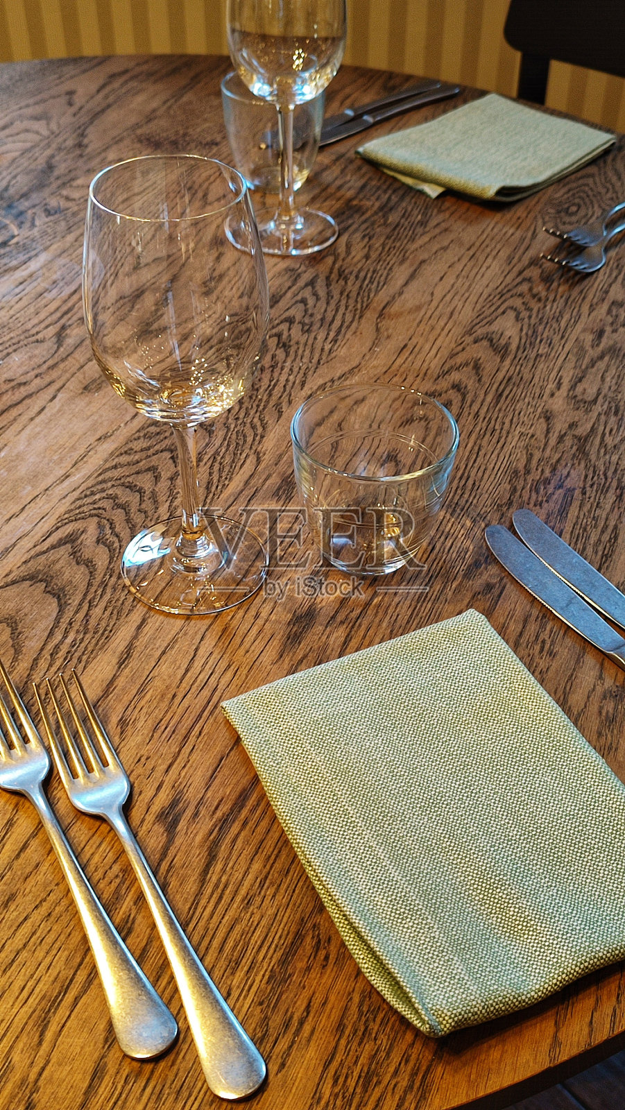 餐厅的木桌子上有玻璃杯,刀叉和绿色餐巾纸照片摄影图片