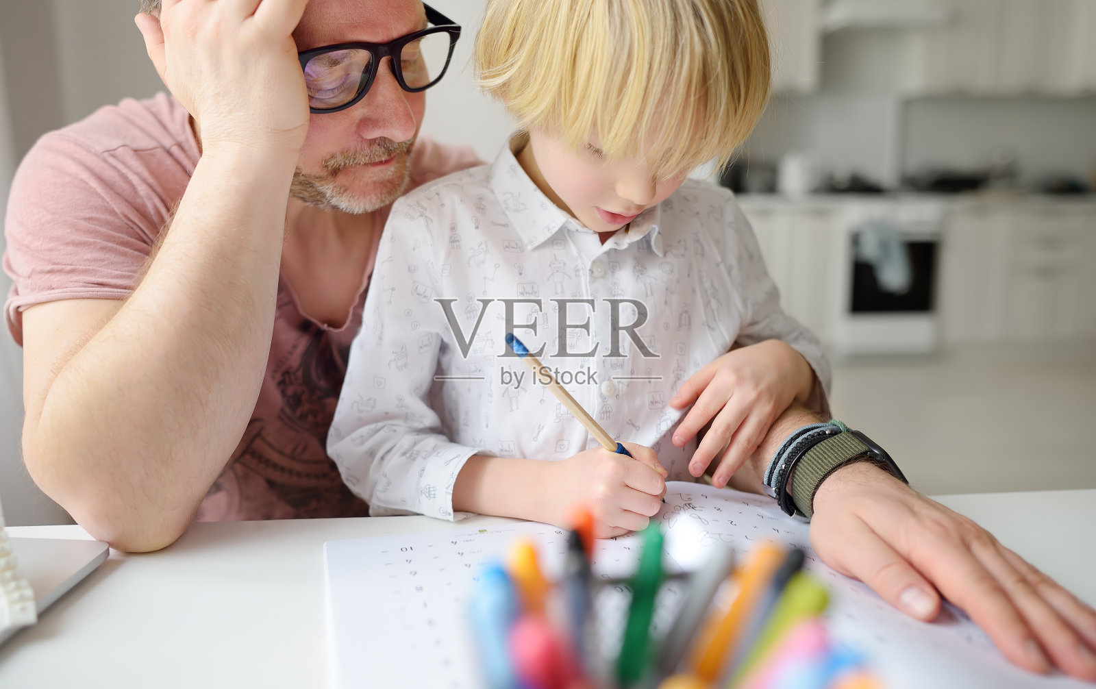 疲惫的父亲帮助患有ADHD的学龄男孩在家做作业。在家上学,远程学习,在线学习,儿童远程教育。照片摄影图片