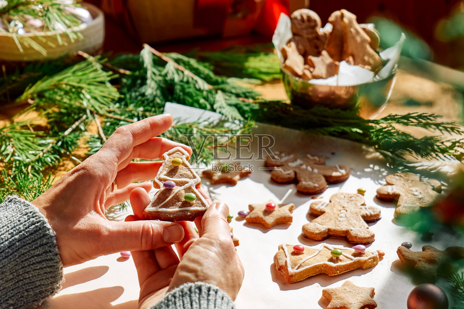 女人的手装饰釉面圣诞姜饼饼干形状的姜饼人,圣诞树和星星,装饰彩色糖杏仁。圣诞节和新年的传统节日食物。照片摄影图片