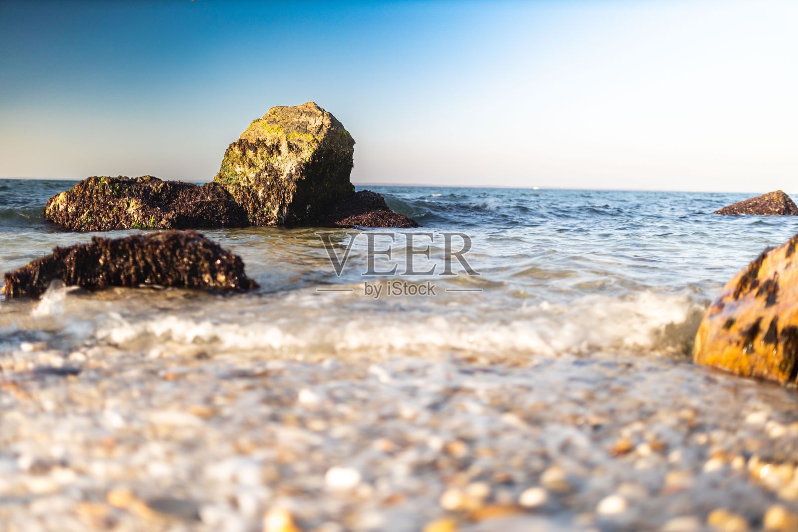 日落时分,海滩上的岩石和晴朗的天空照片摄影图片