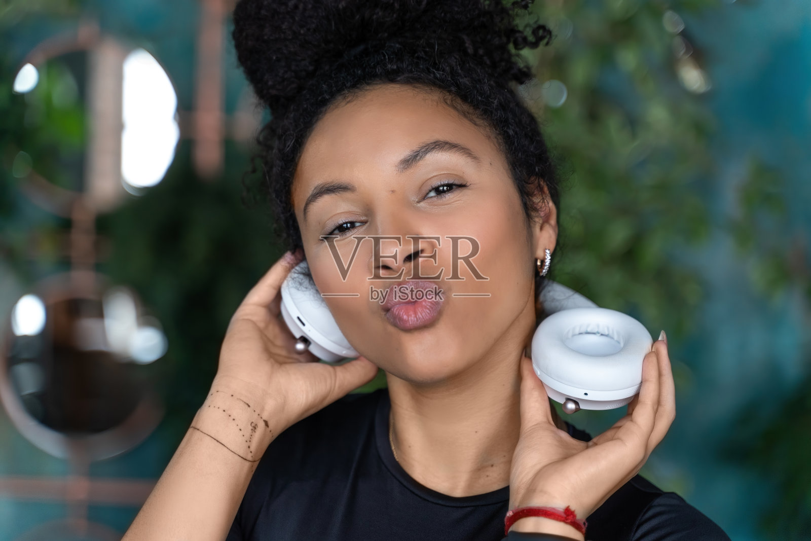 美丽的年轻黑人妇女戴着时尚的白色耳机在黑暗的阁楼公寓背景。复制空间,模型,模板,空白。青少年日常生活中的音乐观念照片摄影图片