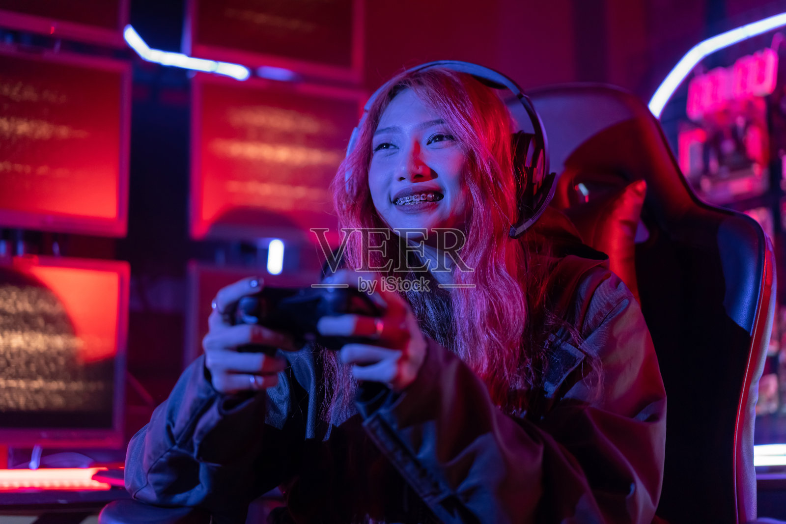 你赢了。玩家用摇杆控制器在电脑霓虹灯背景下玩在线视频游戏,女人用游戏耳机在家里玩直播电竞游戏。照片摄影图片