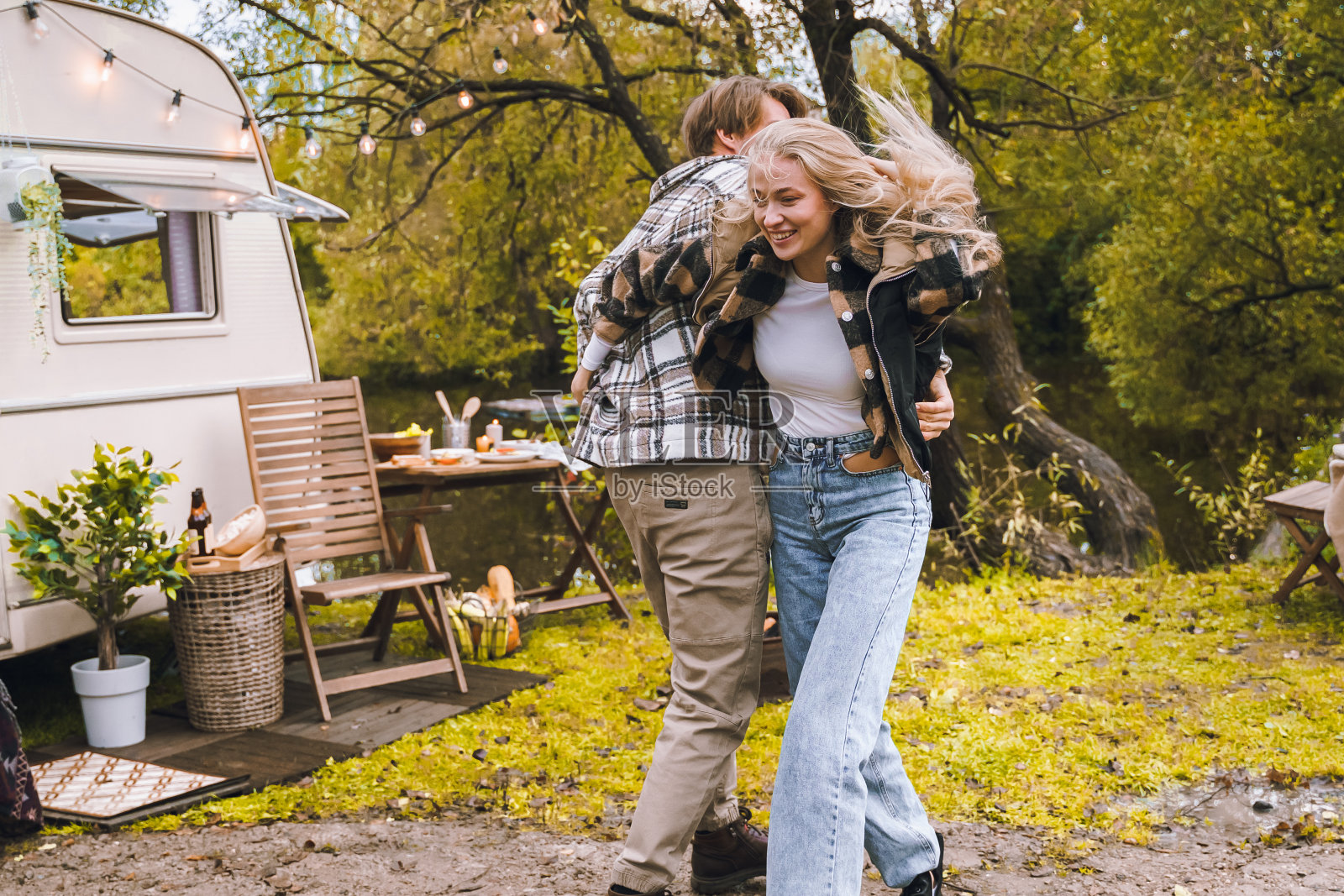 年轻的新婚夫妇在露营车里旅行,有轮子的房子,拖车,房车。热爱浪漫的公路旅行,自由的生活。在货车里露营过夜。旅游热假期,周末。女孩,家伙,快乐的冒险照片摄影图片