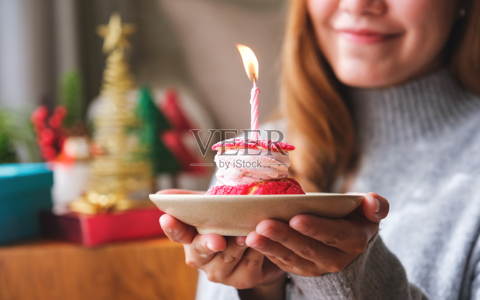 一个年轻女子拿着生日蛋糕和蜡烛的特写图像,圣诞节的节日装饰在家里照片摄影图片