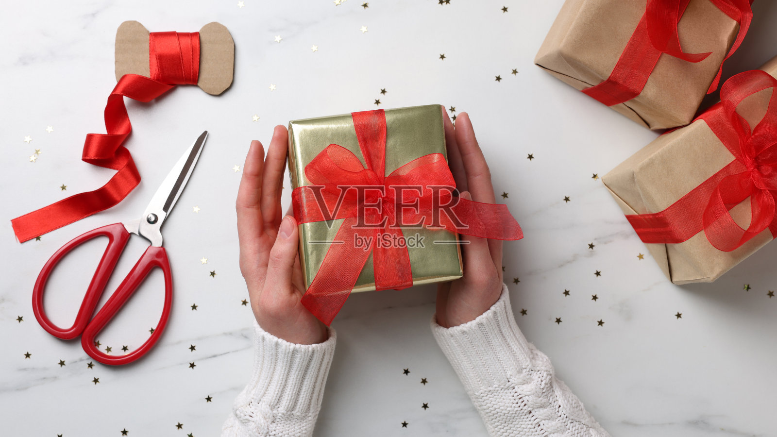 妇女与包装圣诞礼盒在白色大理石桌子,俯视图照片摄影图片
