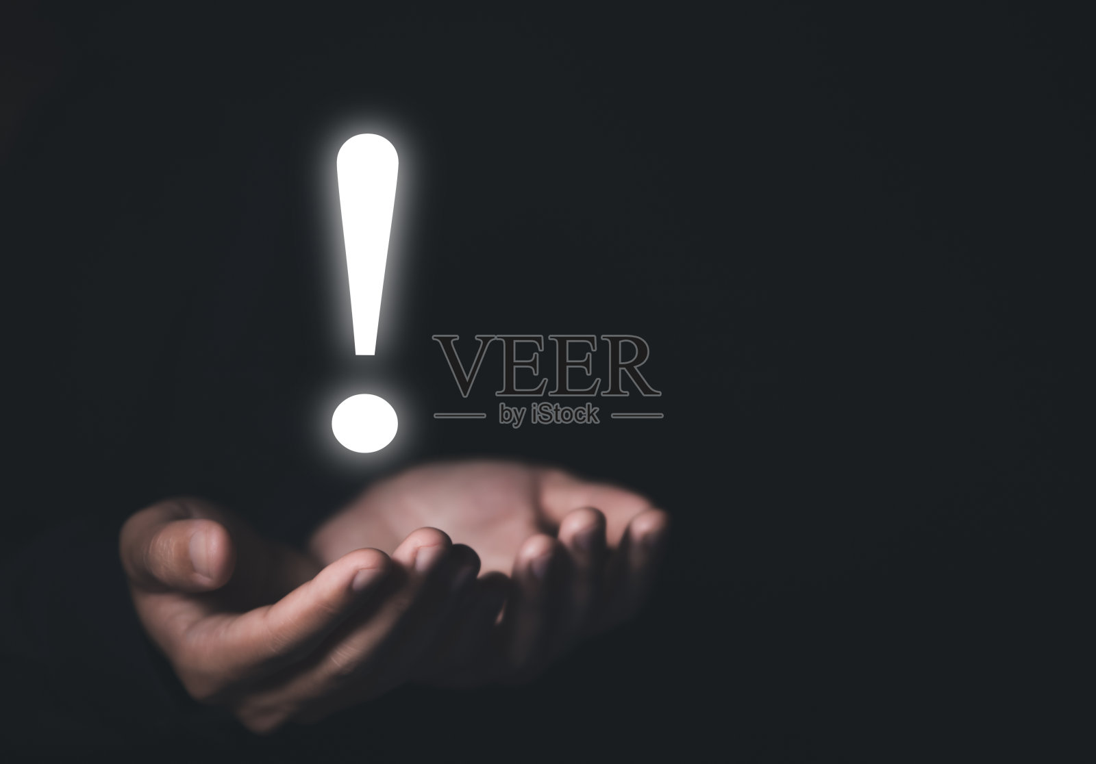 一个商人的两只手在黑色背景上显示一个明亮的白色感叹号照片摄影图片