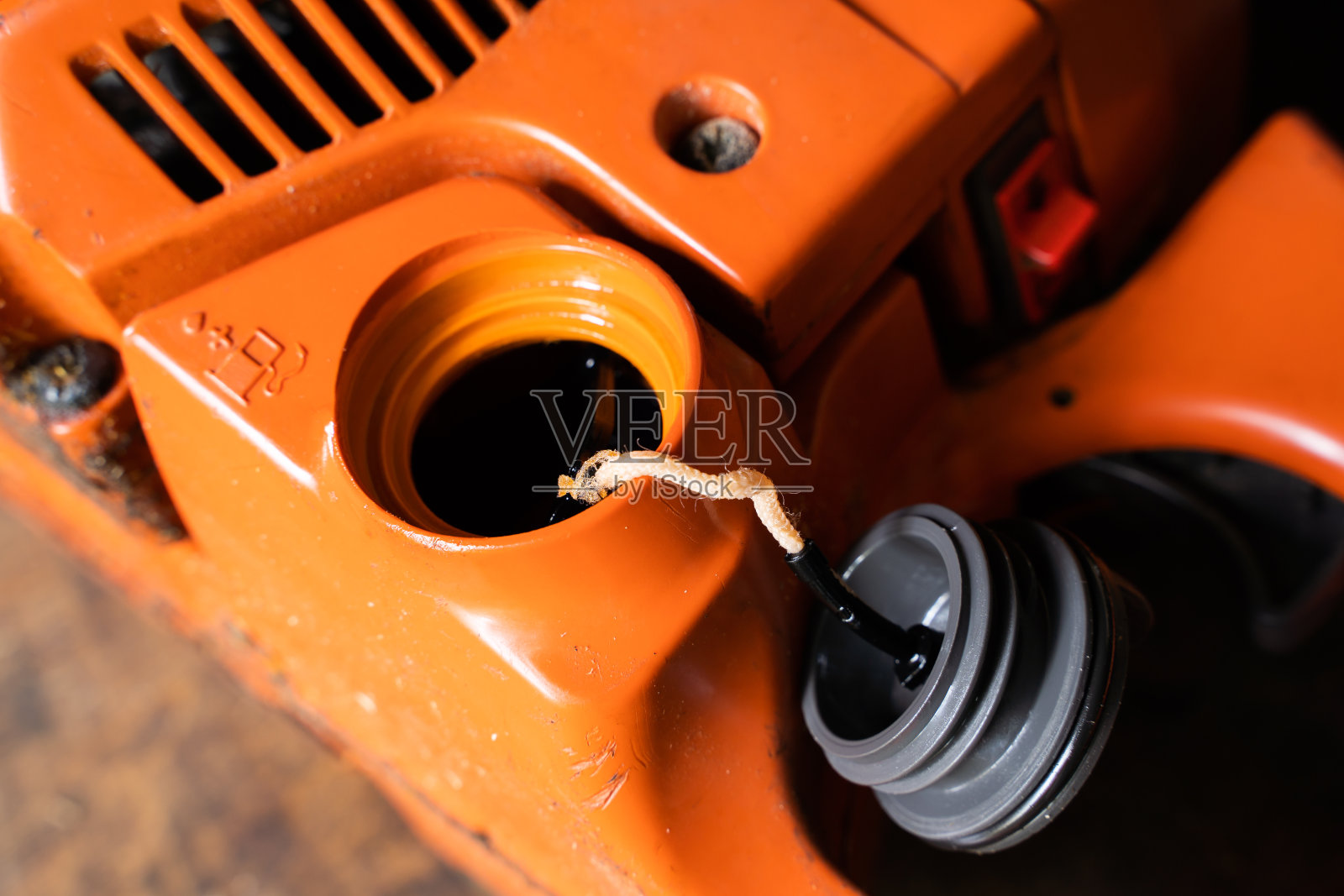 打开链锯中燃油混合物的填充颈。正在给二冲程发动机的油箱加油照片摄影图片