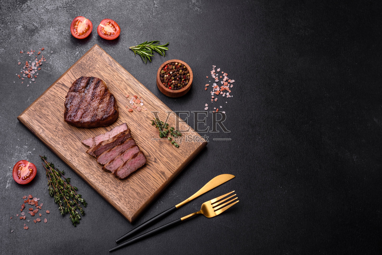 美味多汁的牛排配上香料和香草,背景是深色混凝土照片摄影图片