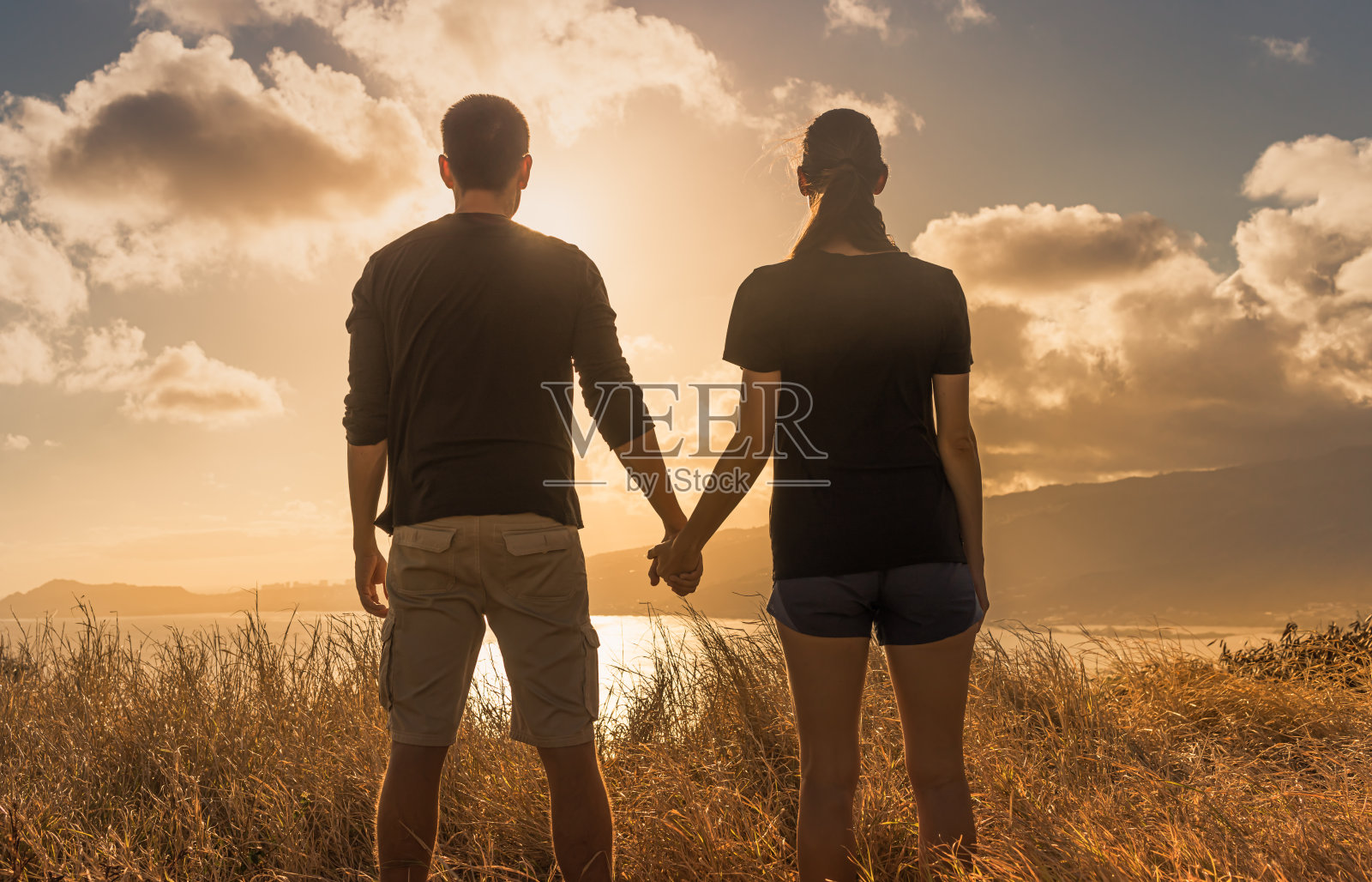夕阳下的情侣手牵着手照片摄影图片