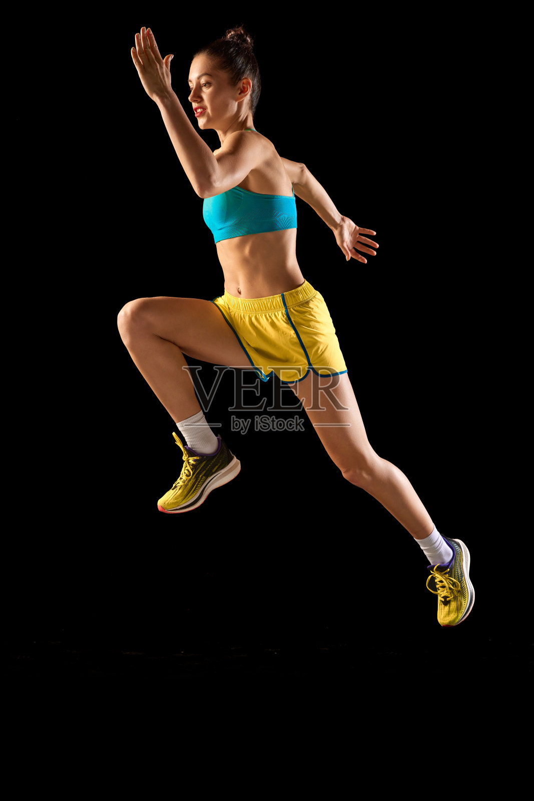 一个穿着运动服的活泼女孩在黑色背景上跳得很高。运动的概念,美,行动,成就,爱好照片摄影图片